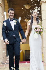 Brautpaar nach der Hochzeit im Regen aus Rosenblättern und Reiskörnern - GEMF000460