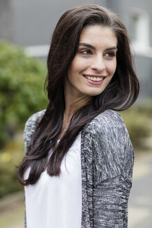 Porträt einer lächelnden jungen Frau mit langen braunen Haaren - GDF000887