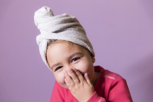 Porträt eines lachenden kleinen Mädchens, das den Mund mit den Händen bedeckt und einen Handtuchturban trägt - ERLF000068
