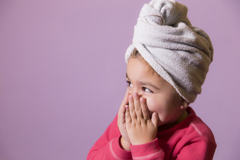 Portrait of little girl covering mouth with her hands wearing towel turban stock photo