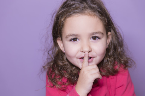 Porträt eines kleinen Mädchens mit Finger auf dem Mund, lizenzfreies Stockfoto