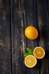 Sliced and whole orange on dark wood - CSF026640