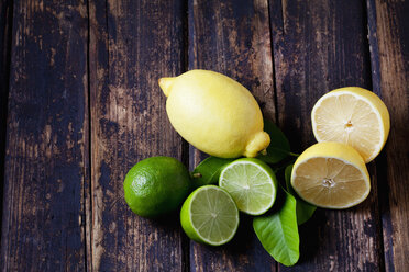 Whole and sliced lemons and limes on dark wood - CSF026647