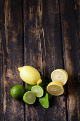 Whole and sliced lemons and limes on dark wood - CSF026648