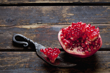 Sliced pomegranate and a knife on dark wood - CSF026676