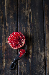 Sliced pomegranate and a knife on dark wood - CSF026677