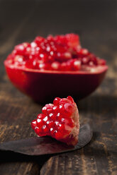 Piece of sliced pomegranate on knife blade and dark wood - CSF026678