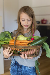 Porträt eines Mädchens, das einen Weidenkorb mit frischem Gemüse hält - SARF002287