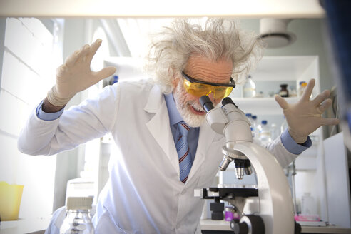 Tousled professor examining samples under microscope, looking surprised - RMAF000191