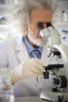 Tousled professor examining samples under microscope - RMAF000192