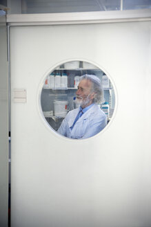 Seniorprofessor schaut durch das Fenster der Labortür - RMAF000197