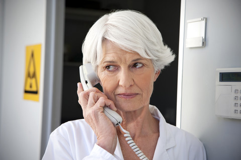 Ältere Frau arbeitet im Labor und telefoniert, lizenzfreies Stockfoto