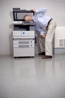 Senior man putting head in copying machine - RMAF000204