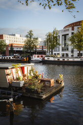 Netherlands, Amsterdam, Houseboat at Amstel river with Het Muziektheater in background - EVGF002491