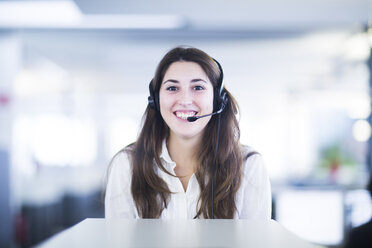 Portrait of smiling young woman with headset in an office - SGF001945