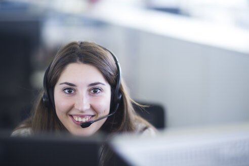 Portrait of smiling young woman with headset at her workplace - SGF001951