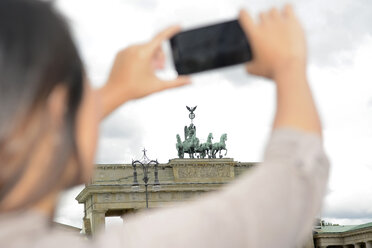 Deutschland, Berlin, junger Tourist fotografiert Brandenburger Tor mit Smartphone - BFRF001600