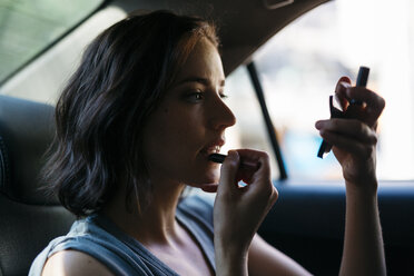 Porträt einer jungen Frau, die in einem Taxi Make-up aufträgt - GIOF000401