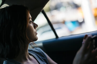 Profile of young woman sitting inside of a cab - GIOF000402