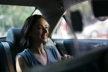 Portrait of happy young woman sitting inside of a cab - GIOF000404