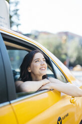 USA, New York City, Porträt einer lächelnden jungen Frau, die durch das Fenster eines gelben Taxis schaut - GIOF000408