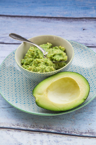 Schale mit Guacamole und halber Avocado auf einem Teller, lizenzfreies Stockfoto