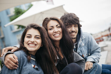 Italy, Rimini, portrait of three happy friends embracing outdoors - GIOF000444