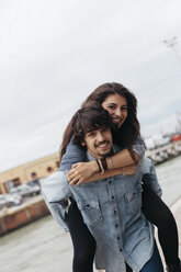 Italien, Rimini, junger Mann trägt seine Freundin huckepack - GIOF000447