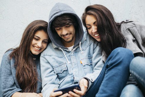 Drei Freunde im Freien schauen auf ihr Handy - GIOF000452