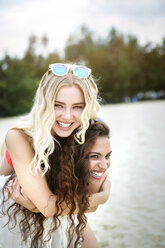 Germany, Haltern, young woman giving her female friend a piggyback ride - GDF000901