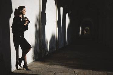 Young woman standing against a wall in an arcade - GIOF000466