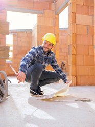 Portrait of foreman with construction plan and pocket rule at construction site - LAF001540