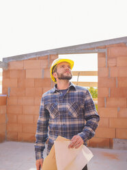 Portrait of foreman with construction plan checking work at construction site - LAF001542