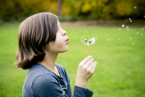 Mädchen bläst Pusteblume, lizenzfreies Stockfoto