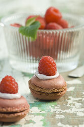 Himbeer-Macarons und Schale mit Himbeeren im Hintergrund - ASF005728