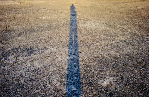 Schatten einer Person auf rissiger Piste, lizenzfreies Stockfoto