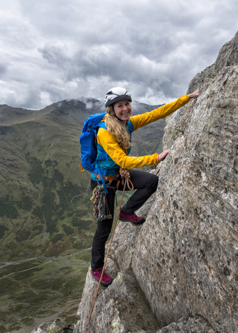 UK, Lake District, Great Langdale, Frau beim Klettern am Pike of Stickle, lizenzfreies Stockfoto