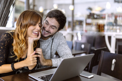 Glückliches junges Paar mit Laptop in einer Kneipe - MGOF001003