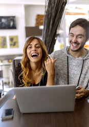 Portrait of laughing young couple with laptop in a pub - MGOF001006