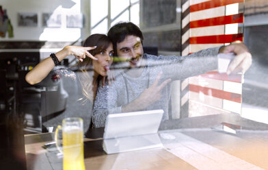 Glückliches junges Paar macht ein Selfie mit Smartphone in einer Kneipe - MGOF001010