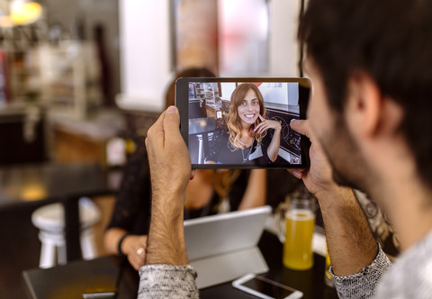 Junger Mann, der seine Freundin mit einem digitalen Tablet fotografiert, lizenzfreies Stockfoto