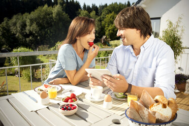 Happy couple having breakfast on balcony - TOYF001417