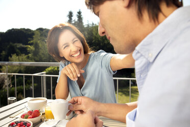 Happy couple having breakfast on balcony - TOYF001427