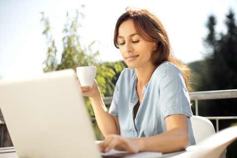 Frau auf Balkon mit Laptop, lizenzfreies Stockfoto