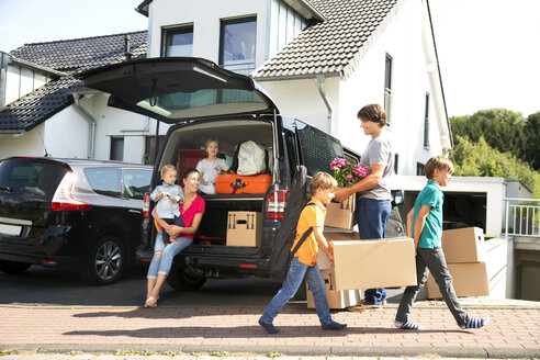 Glückliche Familie bei der Einfahrt mit Kartons - TOYF001439