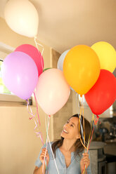 Glückliche Frau steht und hält bunte Luftballons - TOYF001445