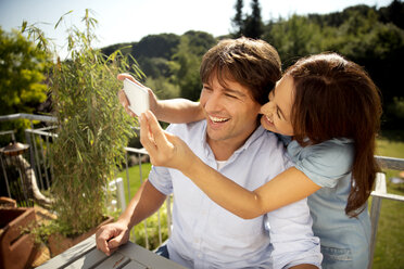 Happy couple on balcony taking a selfie - TOYF001457