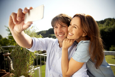 Glückliches Paar auf dem Balkon macht ein Selfie - TOYF001460