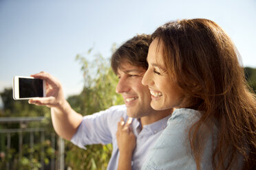 Happy couple outdoors taking a selfie - TOYF001462