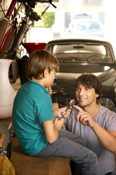 Father and son in garage with vintage car and tools - TOYF001463